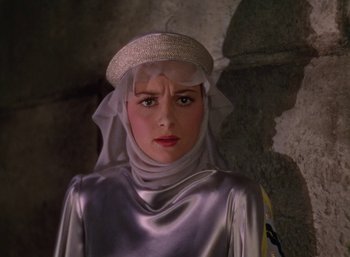 Movie still from “The Adventures of Robin Hood” (1938), directed by William Keighley – A woman wearing a silver outfit and a white hat; Close Up shot, Over the shoulder angle