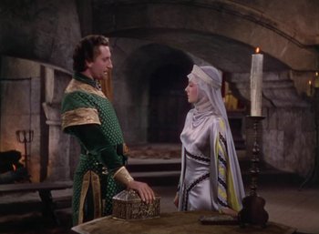Movie still from “The Adventures of Robin Hood” (1938), directed by William Keighley – A man and a woman dressed in medieval garb stand in front of a fireplace; Medium shot, High angle