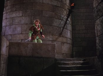 Movie still from “The Adventures of Robin Hood” (1938), directed by William Keighley – A man dressed as robin hood standing on top of a stone wall; Wide shot, High angle