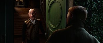 Movie still from “The Adventures of Tintin” (2011), directed by Steven Spielberg – A man in a striped shirt talking to another man in front of a green door; Medium shot, Over the shoulder angle