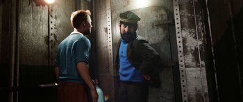 Movie still from “The Adventures of Tintin” (2011), directed by Steven Spielberg – Two men standing next to each other near a wall; Medium shot, Over the shoulder angle