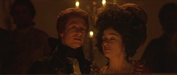 Movie still from “The Affair of the Necklace” (2001), directed by Charles Shyer – A man and a woman standing next to each other in front of lights; Close Up shot, Low angle