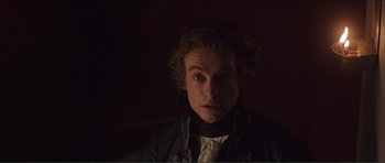 Movie still from “The Affair of the Necklace” (2001), directed by Charles Shyer – A young man with long curly hair wearing a black jacket; Close Up shot, Over the shoulder angle