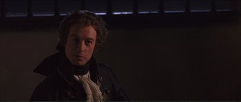 Movie still from “The Affair of the Necklace” (2001), directed by Charles Shyer – A man in a black shirt and a white scarf; Close Up shot, Over the shoulder angle