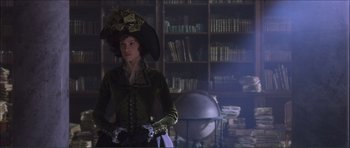 Movie still from “The Affair of the Necklace” (2001), directed by Charles Shyer – A woman in a green dress and a black hat; Medium shot, Over the shoulder angle