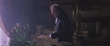 Movie still from “The Affair of the Necklace” (2001), directed by Charles Shyer – A man in black jacket standing in front of a table; Medium shot, Low angle