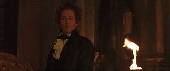 Movie still from “The Affair of the Necklace” (2001), directed by Charles Shyer – A man with curly hair wearing a black jacket and a white bow tie; Medium shot, Low angle