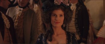 Movie still from “The Affair of the Necklace” (2001), directed by Charles Shyer – A young woman with long dark hair wearing a hat; Close Up shot, Over the shoulder angle