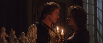 Movie still from “The Affair of the Necklace” (2001), directed by Charles Shyer – A man and a woman standing in front of lit candles; Medium shot, Over the shoulder angle