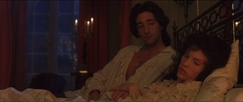 Movie still from “The Affair of the Necklace” (2001), directed by Charles Shyer – A man in white shirt laying on a bed next to candles; Medium shot, High angle