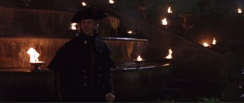 Movie still from “The Affair of the Necklace” (2001), directed by Charles Shyer – A man in a pirate hat standing in front of a fountain; Medium shot, Over the shoulder angle