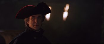 Movie still from “The Affair of the Necklace” (2001), directed by Charles Shyer – A person wearing a hat with lights in the background; Close Up shot, Over the shoulder angle