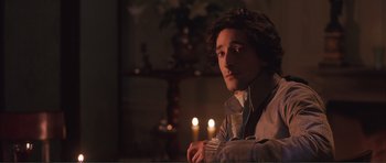 Movie still from “The Affair of the Necklace” (2001), directed by Charles Shyer – A man sitting in front of a lit candle; Close Up shot, Over the shoulder angle