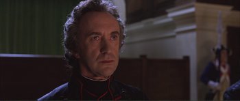 Movie still from “The Affair of the Necklace” (2001), directed by Charles Shyer – An older man wearing a black shirt and a red tie; Close Up shot, Low angle