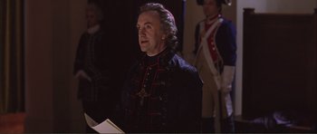 Movie still from “The Affair of the Necklace” (2001), directed by Charles Shyer – A man dressed in a black and red uniform; Medium shot, Over the shoulder angle