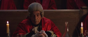 Movie still from “The Affair of the Necklace” (2001), directed by Charles Shyer – An old man wearing a wig and a red robe; Medium shot, High angle