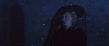 Movie still from “The Affair of the Necklace” (2001), directed by Charles Shyer – A woman in a black coat and a black hat; Close Up shot, Low angle