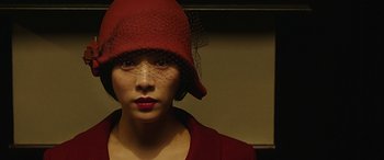 A woman wearing a red cloche hat and lipstick