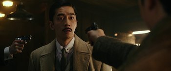 A man holding a gun pointed at a man in a suit