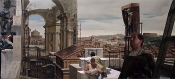 Movie still from “The Agony and the Ecstasy” (1965), directed by Carol Reed – A man sitting on top of a building while a woman stands next to him; Extreme Wide shot, Low angle