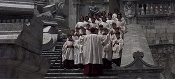 Movie still from “The Agony and the Ecstasy” (1965), directed by Carol Reed – A group of men in white robes standing in front of a building; Wide shot, High angle