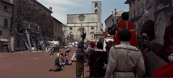 Movie still from “The Agony and the Ecstasy” (1965), directed by Carol Reed – A group of people dressed in medieval costumes in front of an old church; Extreme Wide shot, High angle