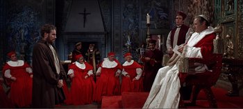 Movie still from “The Agony and the Ecstasy” (1965), directed by Carol Reed – A group of men sitting in a room with a woman; Wide shot, High angle