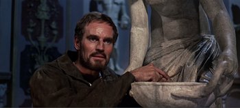 Movie still from “The Agony and the Ecstasy” (1965), directed by Carol Reed – A man is leaning on a statue of a person; Close Up shot, Low angle