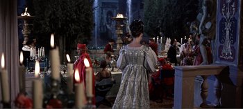 Movie still from “The Agony and the Ecstasy” (1965), directed by Carol Reed – A woman dressed in medieval garb standing in front of a table; Wide shot, Over the shoulder angle