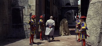 Movie still from “The Agony and the Ecstasy” (1965), directed by Carol Reed – A group of men standing next to each other on a street; Wide shot, Over the shoulder angle