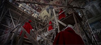 Movie still from “The Agony and the Ecstasy” (1965), directed by Carol Reed – A group of people dressed in red are standing on scaffolding in a building; Extreme Wide shot, Low angle