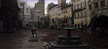 Two people are standing near a fountain in an empty courtyard