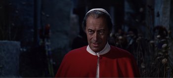 Movie still from “The Agony and the Ecstasy” (1965), directed by Carol Reed – A man wearing a red robe and a white hat; Close Up shot, Over the shoulder angle