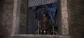 Movie still from “The Agony and the Ecstasy” (1965), directed by Carol Reed – A man standing in a doorway wearing a brown robe; Wide shot, Low angle