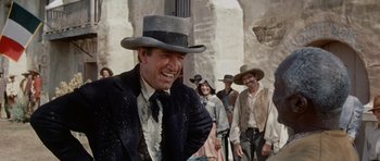 Movie still from “The Alamo” (1960), directed by John Wayne – A group of men in hats and ties standing next to each other on a street; Medium shot, Low angle