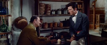 Movie still from “The Alamo” (1960), directed by John Wayne – Two men sitting at a table with a candle; Medium shot, Over the shoulder angle