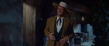 Movie still from “The Alamo” (1960), directed by John Wayne – A man wearing a cowboy hat standing in a room; Medium shot, Low angle