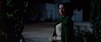 Movie still from “The Alamo” (1960), directed by John Wayne – A woman wearing a green cape and a white dress; Medium shot, Low angle