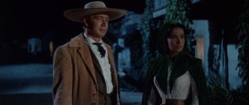 Movie still from “The Alamo” (1960), directed by John Wayne – A man and a woman dressed in western clothing; Medium shot, Low angle