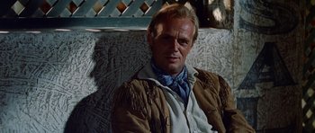 Movie still from “The Alamo” (1960), directed by John Wayne – A person sitting on a wall; Close Up shot, Over the shoulder angle