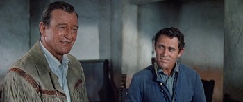 Movie still from “The Alamo” (1960), directed by John Wayne – A man and a woman smiling for the camera; Close Up shot, Over the shoulder angle