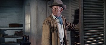 Movie still from “The Alamo” (1960), directed by John Wayne – A man wearing a cowboy hat and a jacket; Medium shot, Low angle