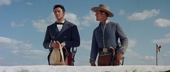 Movie still from “The Alamo” (1960), directed by John Wayne – A couple of men standing next to each other on top of a hill; Medium shot, Low angle