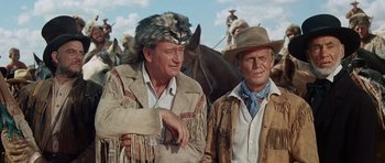 Movie still from “The Alamo” (1960), directed by John Wayne – Two men standing next to each other on horses; Medium shot, Low angle
