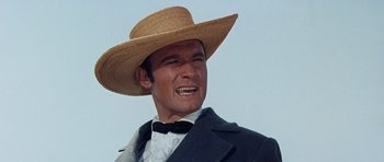 Movie still from “The Alamo” (1960), directed by John Wayne – A man wearing a straw hat and a suit; Close Up shot, Low angle