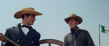 Movie still from “The Alamo” (1960), directed by John Wayne – Two men in hats and jackets standing next to each other; Medium shot, Low angle