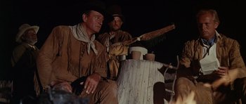Movie still from “The Alamo” (1960), directed by John Wayne – Two men sitting next to each other holding a bat; Medium shot, Low angle