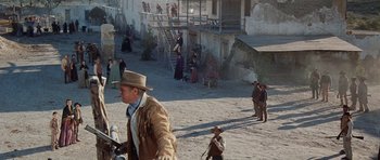 Movie still from “The Alamo” (1960), directed by John Wayne – A group of people standing on top of a dirt field; Extreme Wide shot, High angle
