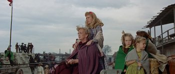 Movie still from “The Alamo” (1960), directed by John Wayne – A woman sitting on the shoulders of a man in a carriage; Medium shot, Low angle