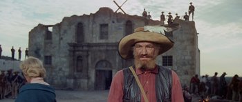 Movie still from “The Alamo” (1960), directed by John Wayne – A man with a beard wearing a cowboy hat; Medium shot, Low angle